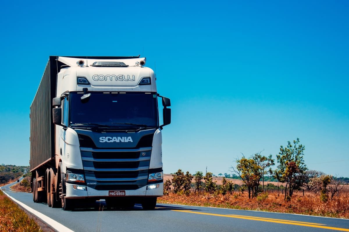 White refrigerated box truck rolling down an open highway